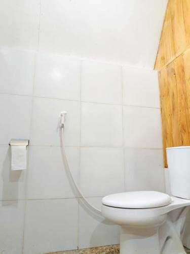 a white bathroom with a toilet and a shower at Forest Side bungalow in Tetebatu