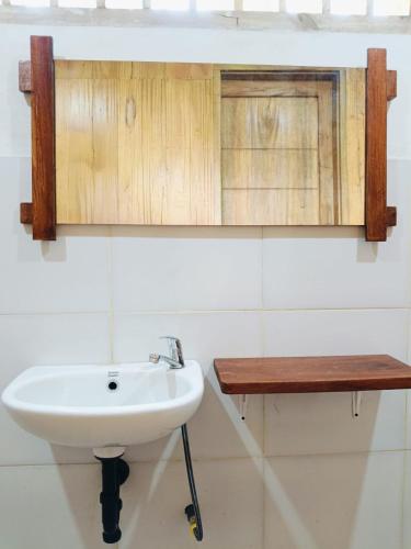 a bathroom with a white sink and a wooden shelf at Forest Side bungalow in Tetebatu