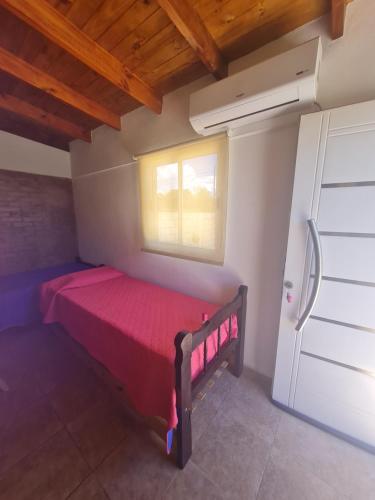 ein kleines Schlafzimmer mit einem roten Bett und einem Fenster in der Unterkunft Dálet in Villa Parque Siquiman