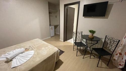 a room with a table and chairs and a television at Pousada Folhas de Outono in Canela