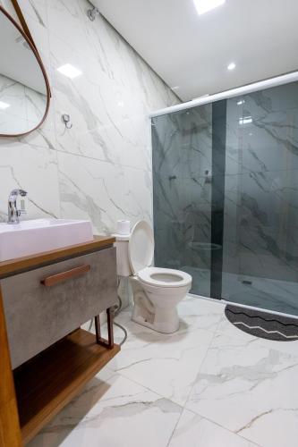 a bathroom with a toilet and a glass shower at Hostel Village GRU in Guarulhos