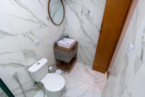 a white bathroom with a toilet and a sink at Hostel Village GRU in Guarulhos