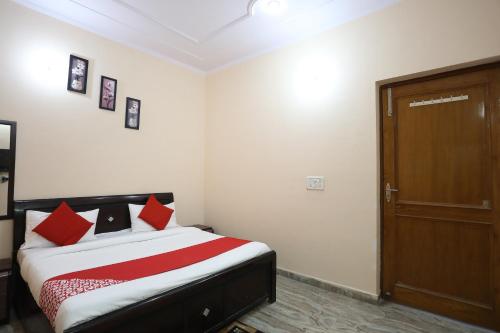 a bedroom with a bed with red pillows and a door at Hotel Krishna Resorts in Mathura