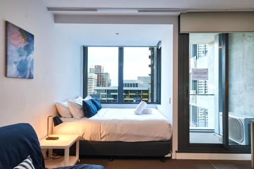 una camera da letto con un letto e una grande finestra di Sky-High Serenity with Stunning Views on Level 32 a Melbourne