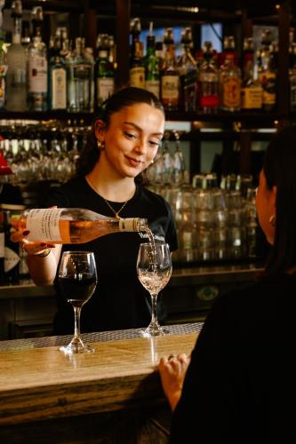 a woman pouring a glass of wine at a bar at Hotel Concord in Sydney