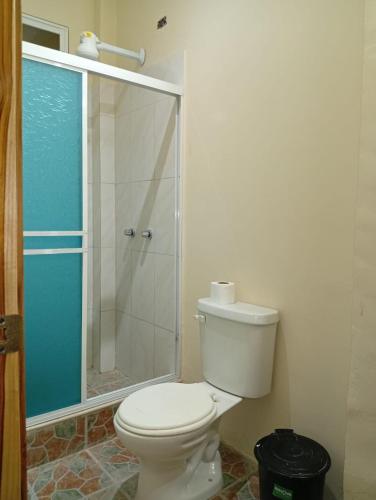 a bathroom with a toilet and a glass shower at Hostal Moai in Montañita