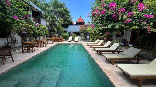 a pool with chairs and tables in a courtyard at Marygio Gili Resort in Gili Trawangan