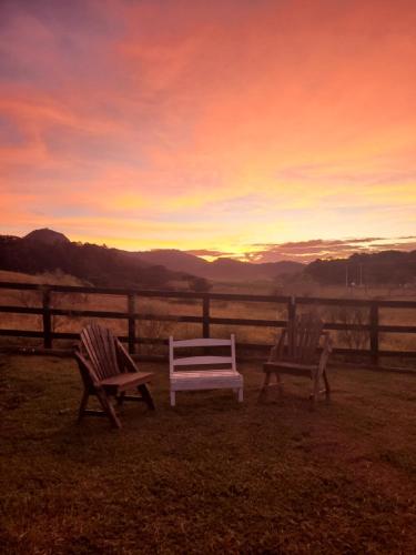 three chairs sitting in the grass with a sunset at Paraiso do Campestre in Urubici