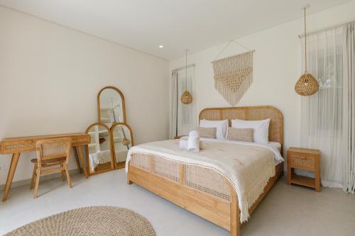 a bedroom with a bed and a table and a mirror at Mata Biru Villa by Betterplace in Uluwatu