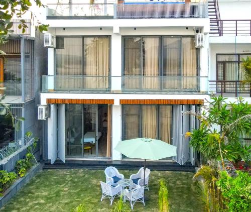 a patio with two chairs and an umbrella in front of a building at Heartland- Ganga Villa with Jacuzzi and private lift in Rishīkesh