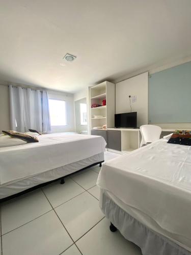 a hotel room with two beds and a tv at Pousada dos Artistas in Campina Grande