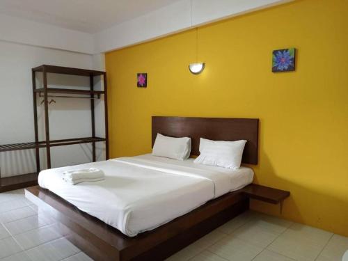 a bedroom with a large bed with a yellow wall at 22 Seasons Hotel in Ban Khlong Chi Lat