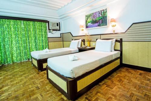 two beds in a room with green curtains at Family Country Hotel and Convention Centre in General Santos