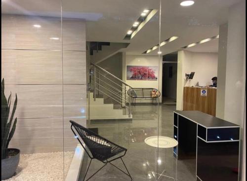 un hall avec un mur de verre et une chaise noire dans l'établissement Studio Coral en la mejor Zona de Cochabamba, à Cochabamba