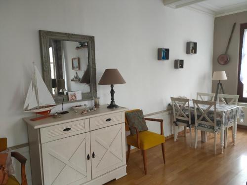 Cette chambre comprend une commode avec un miroir et une table. dans l'établissement Appartement Cosy avec jardinet, à Dieppe