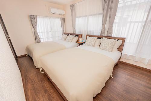 two beds sitting in a room with windows at 華夏民宿 in Tokyo