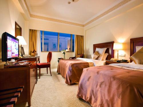 a hotel room with two beds and a flat screen tv at Jiaxing Sunshine Hotel in Jiaxing