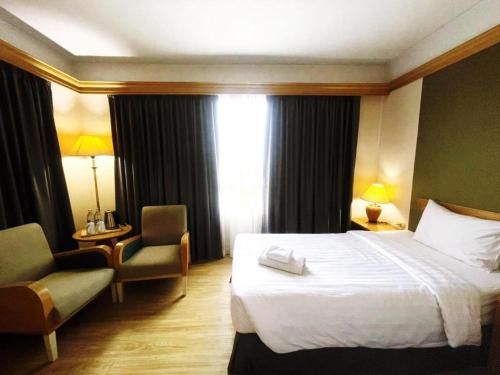 a hotel room with a bed and a chair at Valaya Hotel Pathumthani in Pathum Thani