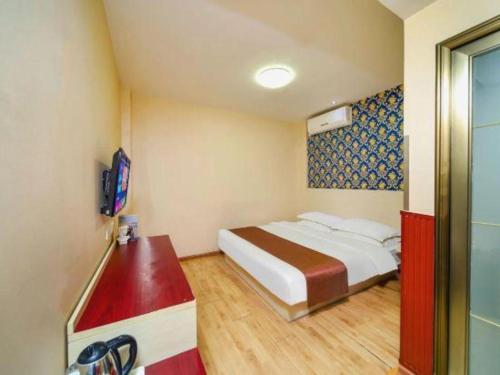 a hotel room with a bed and a television at Kunlun Leju Business Hotel Kaifeng Gulou in Kaifeng