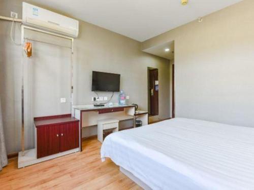 a bedroom with a bed and a desk with a television at Kunlun Leju Business Hotel Kaifeng Gulou in Kaifeng