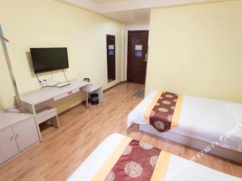 a bedroom with a bed and a tv and a desk at Kunlun Leju Business Hotel Kaifeng Gulou in Kaifeng