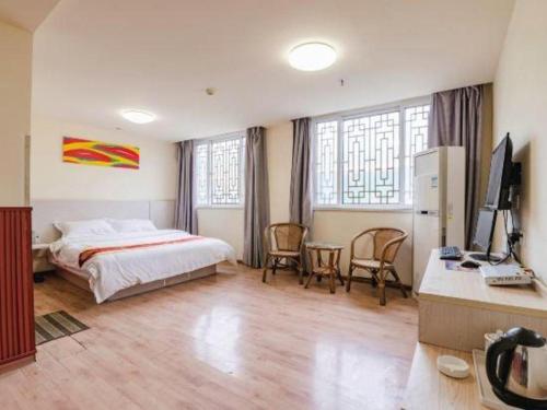 a bedroom with a bed and a desk with a computer at Kunlun Leju Business Hotel Kaifeng Gulou in Kaifeng