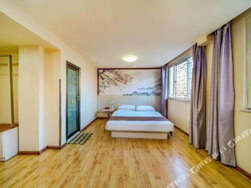 a bedroom with a bed and a painting on the wall at Kunlun Leju Business Hotel Kaifeng Gulou in Kaifeng