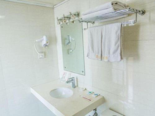 a white bathroom with a sink and a mirror at Kunlun Leju Business Hotel Kaifeng Gulou in Kaifeng