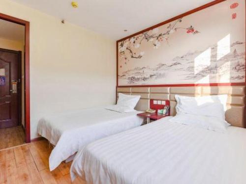 a hotel room with two beds and a painting on the wall at Kunlun Leju Business Hotel Kaifeng Gulou in Kaifeng