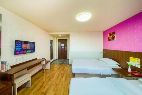 a hotel room with two beds and a pink wall at Kunlun Leju Business Hotel Kaifeng Gulou in Kaifeng