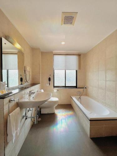 a bathroom with a tub and a toilet and a sink at Khang Residency Thimphu in Thimphu