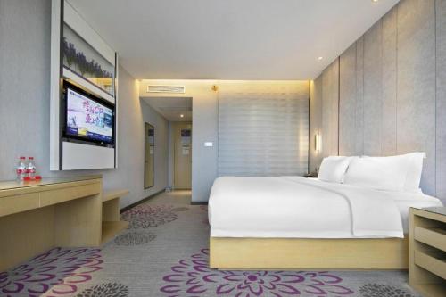 a bedroom with a large white bed and a flat screen tv at Lavande Hotel Yichang Railway East Station Branch in Yichang