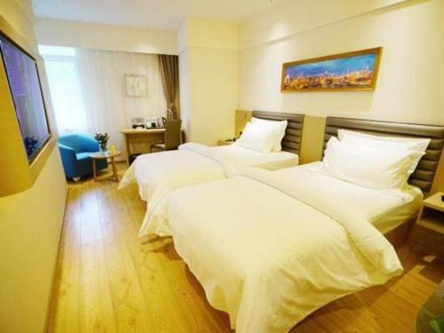 a hotel room with two beds and a flat screen tv at Metropolo Hotel Qingdao Wusi Square Xiaomaidao in Qingdao