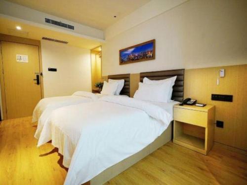 a hotel room with two beds and a telephone at Metropolo Hotel Qingdao Wusi Square Xiaomaidao in Qingdao