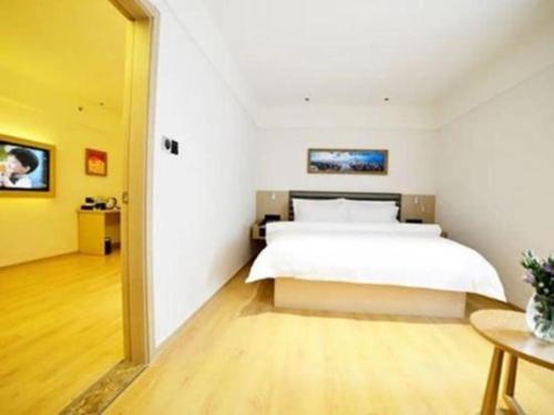 a bedroom with a white bed and a yellow wall at Metropolo Hotel Qingdao Wusi Square Xiaomaidao in Qingdao