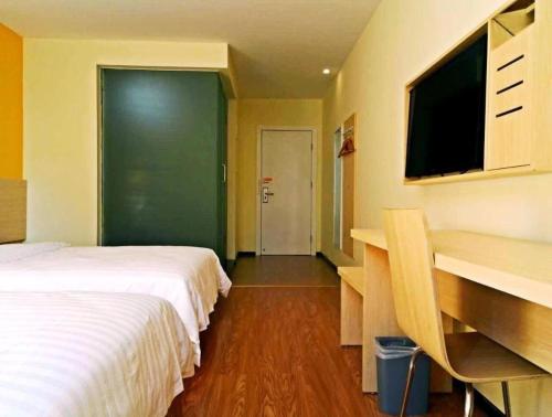a hotel room with two beds and a desk and a television at 7 Days Inn Xingyi Wanfenglin Xiawutun in Xiawutun