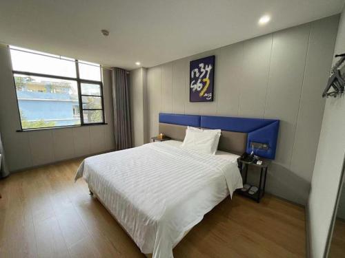 a bedroom with a large bed with a blue headboard at 7 Days Inn Xingyi Wanfenglin Xiawutun in Xiawutun