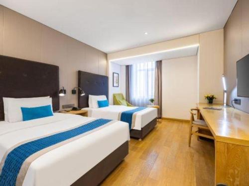 a hotel room with two beds and a desk at Yitel Shenyang Sanhao Street Shengjing Hospital in Shenyang