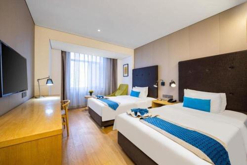 a hotel room with two beds and a flat screen tv at Yitel Shenyang Sanhao Street Shengjing Hospital in Shenyang