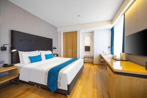 a hotel room with a large bed and a desk at Yitel Shenyang Sanhao Street Shengjing Hospital in Shenyang