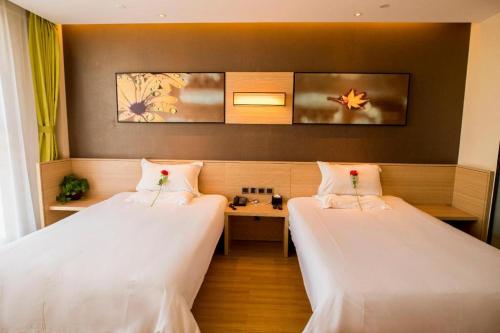 a room with two beds and a table at IU Hotel Zhangye High-Speed Railway Station in Zhangye
