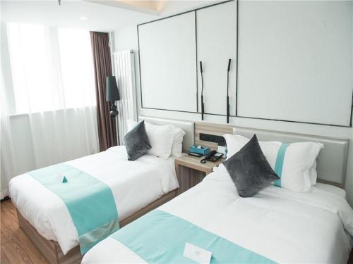 a hotel room with two beds and a mirror at Xana Lite Tianjin Beizhakou Town in Tianjin