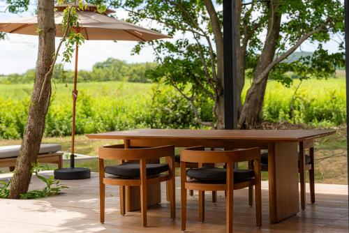 a wooden table with two chairs and an umbrella at SONEKA in Kitahiroshima