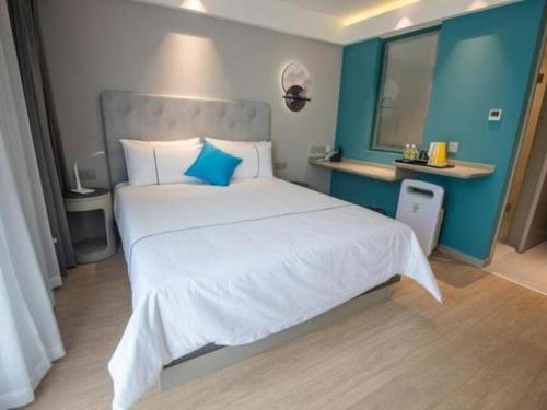 a bedroom with a large white bed with blue walls at Magnotel Hotel Suzhou Guanqian Street Pingjiang Road in Suzhou