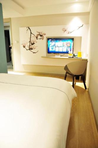 a bedroom with a bed and a tv on a wall at Magnotel Hotel Suzhou Guanqian Street Pingjiang Road in Suzhou
