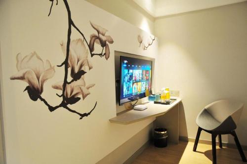 a room with a desk with a computer on a wall at Magnotel Hotel Suzhou Guanqian Street Pingjiang Road in Suzhou