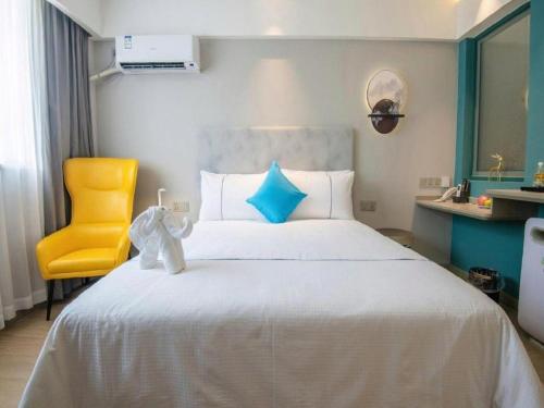 a bedroom with a bed and a yellow chair at Magnotel Hotel Suzhou Guanqian Street Pingjiang Road in Suzhou