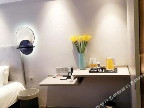 a room with a table with a vase of yellow flowers at Magnotel Hotel Suzhou Guanqian Street Pingjiang Road in Suzhou