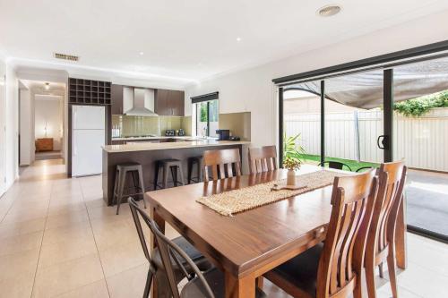 a dining room and kitchen with a wooden table and chairs at Parkview - Echuca Holiday Homes in Moama