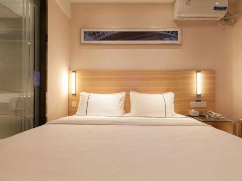 a bedroom with a large bed with white pillows at City Comfort Inn Wuhan Guanggu Textile University in Wuhan